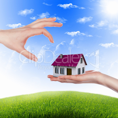 House and human hand against blue sky