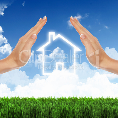 House and human hand against blue sky