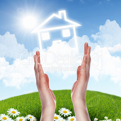 House and human hand against blue sky