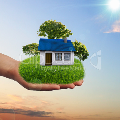 House and human hand against blue sky