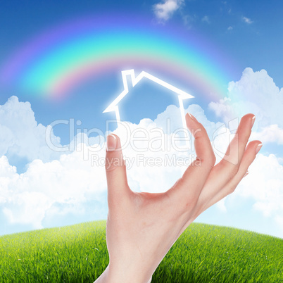 House and human hand against blue sky