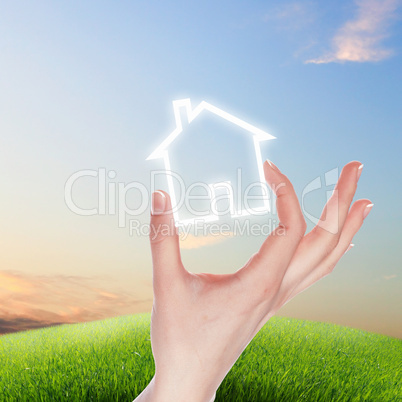 House and human hand against blue sky