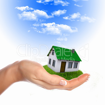 House and human hand against blue sky