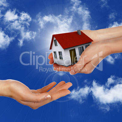 House and human hand against blue sky