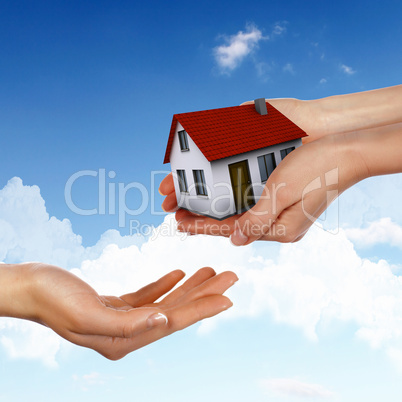 House and human hand against blue sky