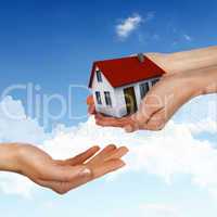 House and human hand against blue sky