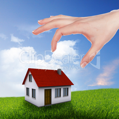 House and human hand against blue sky