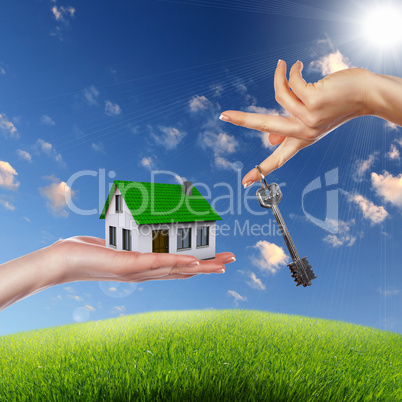 House and human hand against blue sky