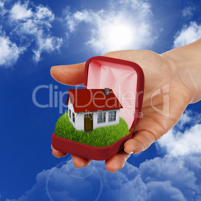 House and human hand against blue sky