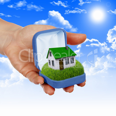 House and human hand against blue sky