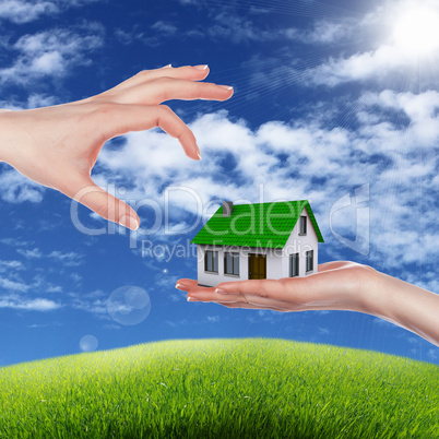 House and human hand against blue sky