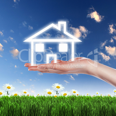 House and human hand against blue sky