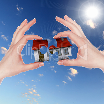 House and human hand against blue sky