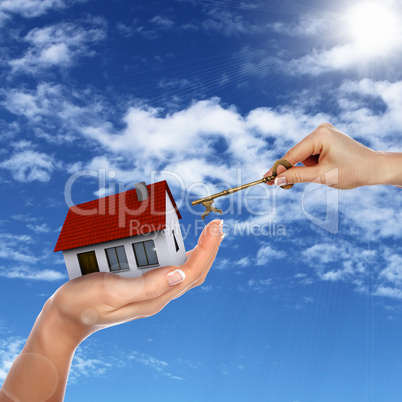 House and human hand against blue sky