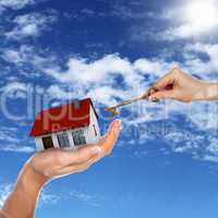 House and human hand against blue sky