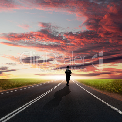 Man walking away at dawn along road