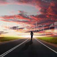 Man walking away at dawn along road