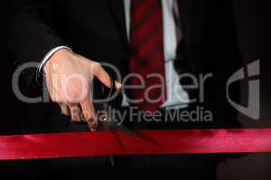 Businessman with scissors cuting a red ribbon