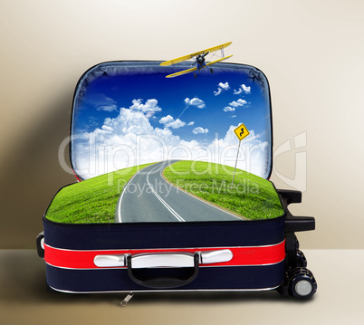Red suitcase with landscape and road inside