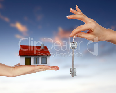 Human hands and house against blue sky