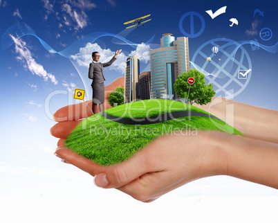 Human hand holding a green landscape