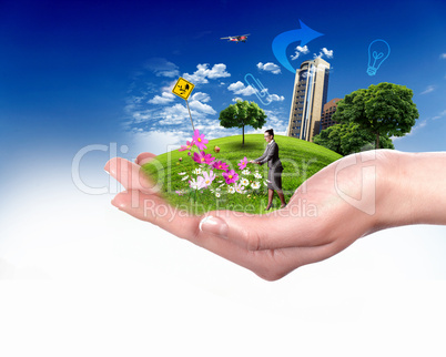 Human hand holding a green landscape