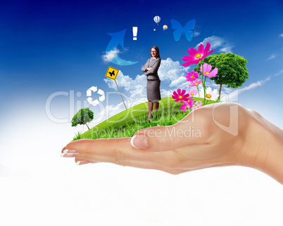 Human hand holding a green landscape