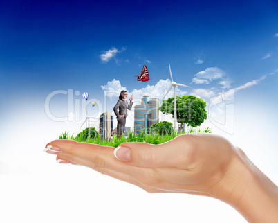 Human hand holding a green landscape