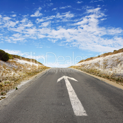 Empty countryside road with white arrow