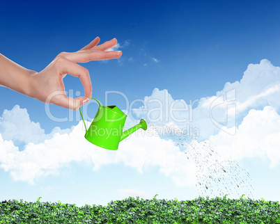 Human hand watering green grass