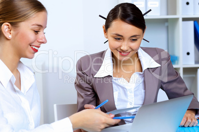 Young women in business wear working in office