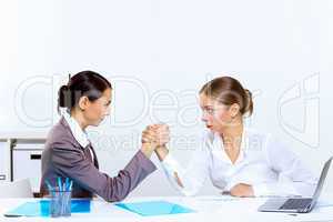 Young women arm wrestling in office