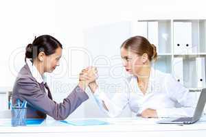 Young women arm wrestling in office