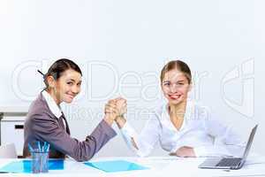 Young women arm wrestling in office