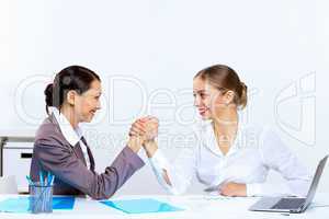 Young women arm wrestling in office