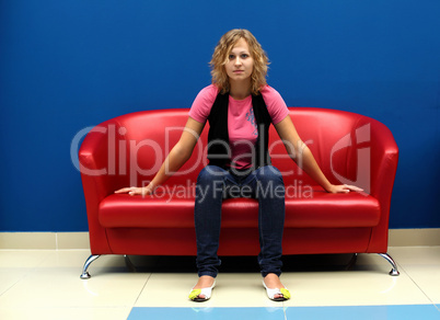 Young woman sitting on red sofa