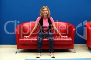 Young woman sitting on red sofa