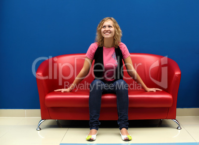 Young woman sitting on red sofa