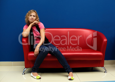 Young woman sitting on red sofa
