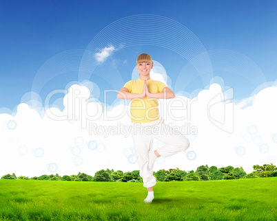 Young woman doing yoga against blue sky