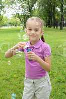 Little girl in the park blowing bubbles