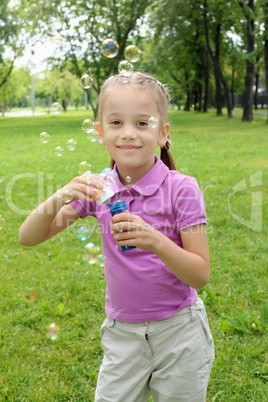 Little girl in the park blowing bubbles