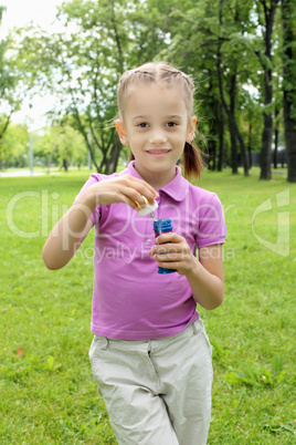 Little girl in the park blowing bubbles