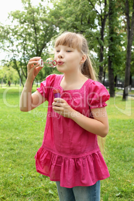 Little girl in the park blowing bubbles