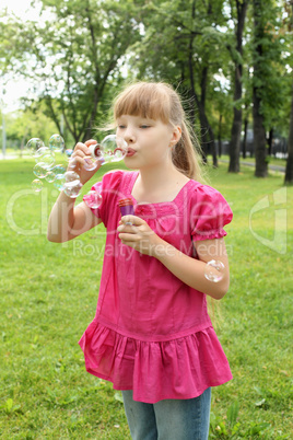 Little girl in the park blowing bubbles