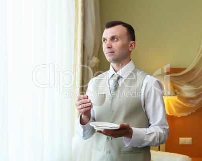 young businessman near the window drinking tea