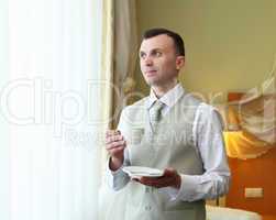 young businessman near the window drinking tea