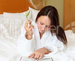 young woman in bed reading a book