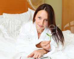 young woman in bed reading a book