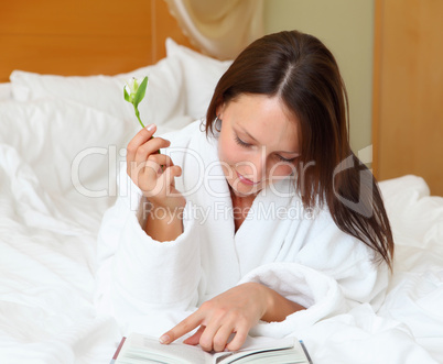 young woman in bed reading a book